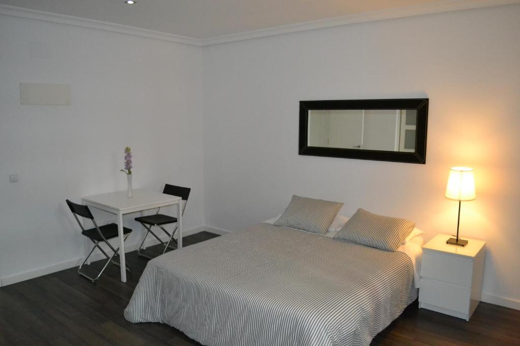 马德里大街公寓酒店的一间卧室配有一张床、一张桌子和一面镜子