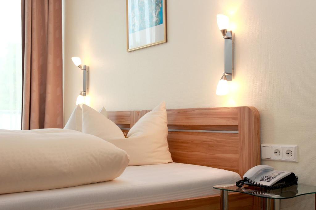 巴特萨尔奇利夫库帕克舍贝尔酒店的一张带白色枕头的床和一张桌子上的电话