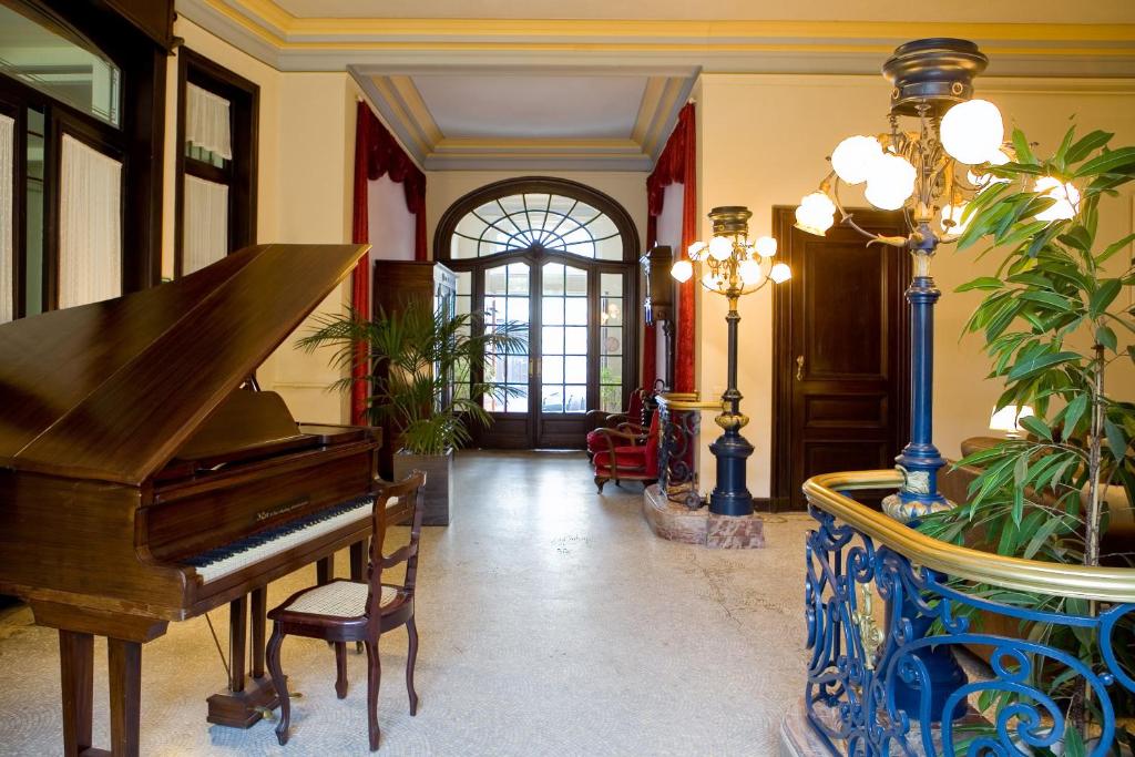 根特汉斯劳特查姆酒店的客厅配有钢琴和蓝色花瓶