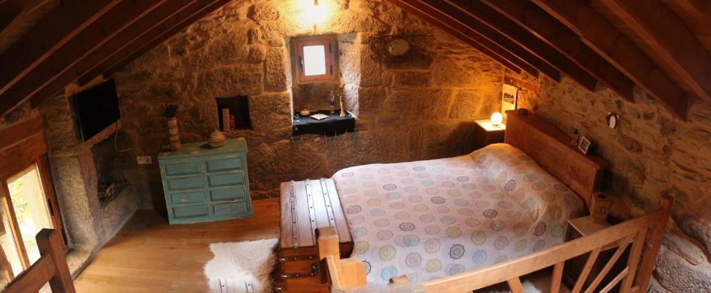奥伦塞Bodega rural tipo loft的石头建筑中的阁楼卧室,配有一张床