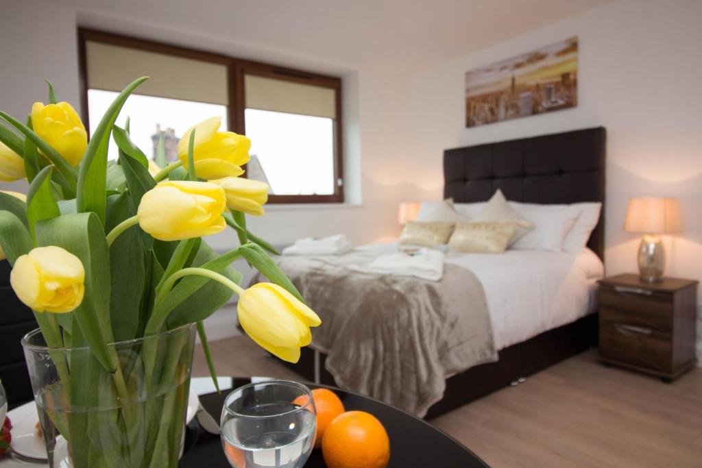 特伦特河畔斯托克Trafalgar House的一间卧室配有床和黄色花瓶