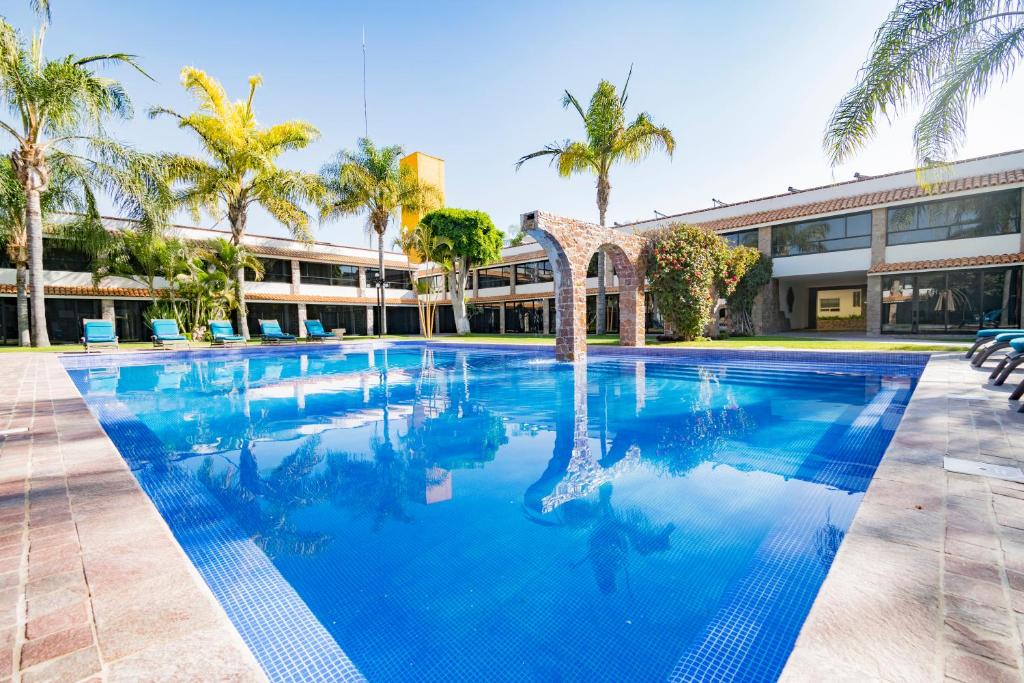 莱昂瑞奥米娜斯薄路瑞木酒店的一座大型游泳池,在一座建筑前种有棕榈树