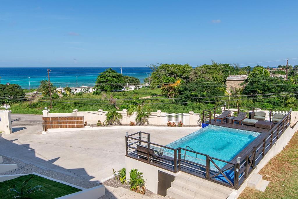 蒙特哥贝Luxury 2BR Home facing Beach w/Pool Montego Bay #5的一个带椅子的游泳池,背景是大海