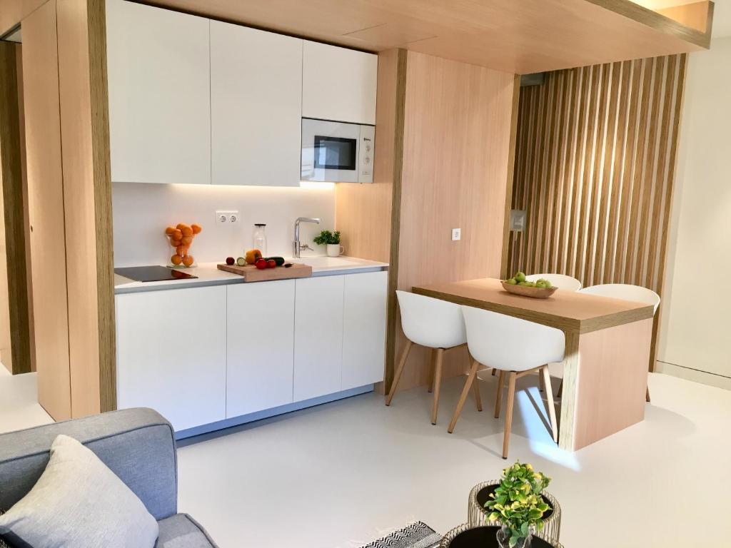 毕尔巴鄂Inside Bilbao Apartments的厨房配有白色橱柜和桌椅