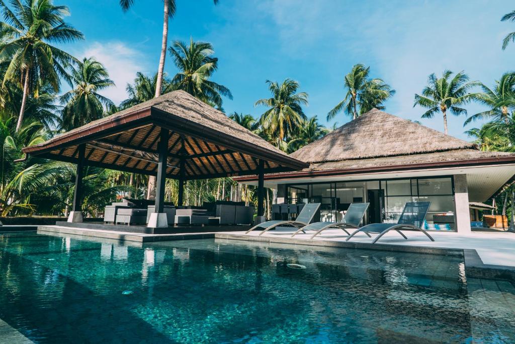 塔林甘海滩乐莫图度假屋的一个带椅子和棕榈树的游泳池的度假酒店
