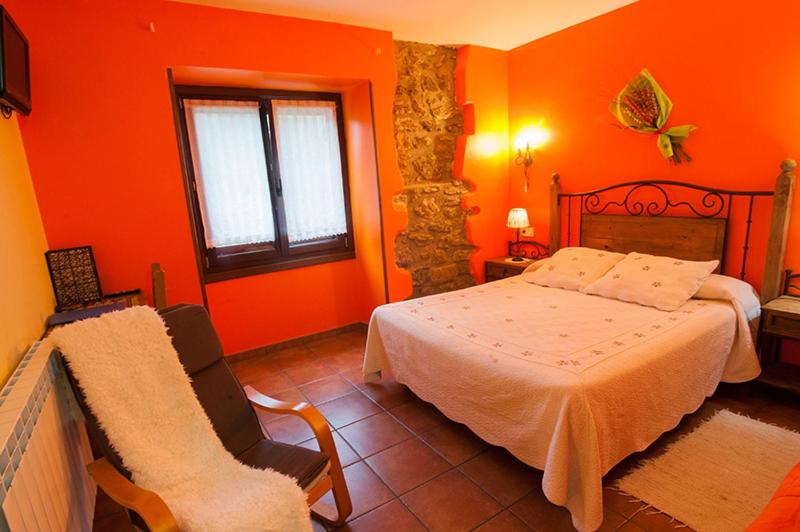 扎马亚Zubeltzu Torre的一间卧室拥有橙色的墙壁,配有一张床和椅子