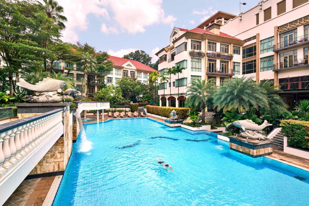 新加坡Treetops Executive Residences的度假村的游泳池,人们在里面游泳