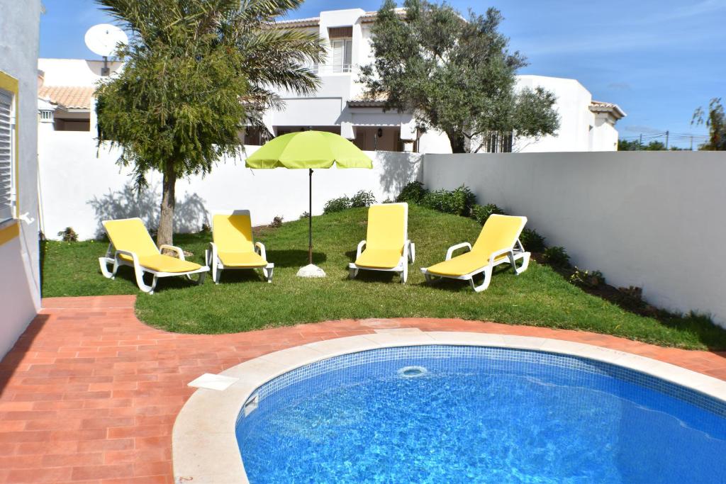吉亚Villa Amendoeira-POOL HEATED的一组椅子、一把遮阳伞和一个游泳池