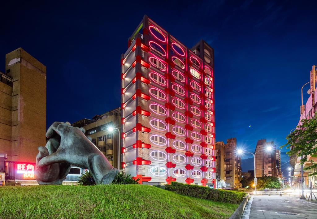 台北Hotelpoispois泡泡饭店的一座高大的红色建筑,前面有雕像