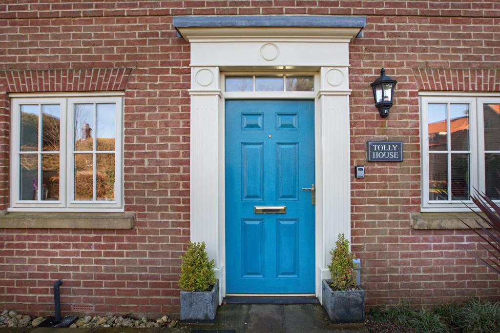 海滨韦尔斯港Tolly House的一条有街道标志的砖砌建筑上的蓝色门