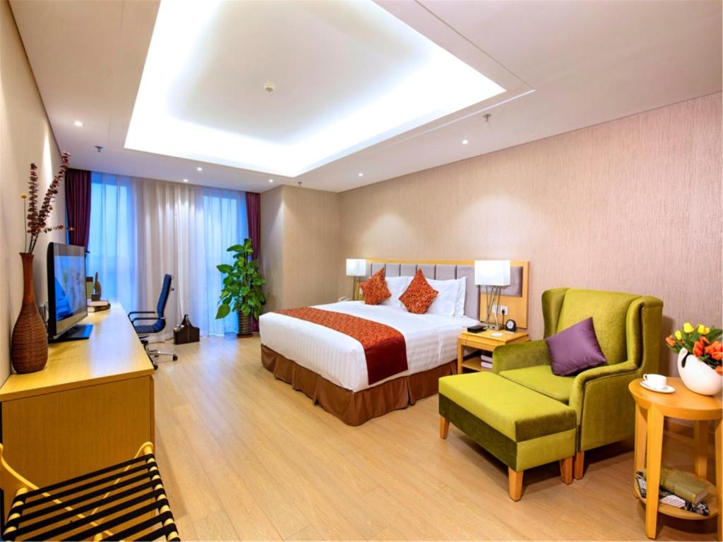 天津天津中北艾丽华酒店及服务公寓的酒店客房,配有一张床和一把绿色椅子