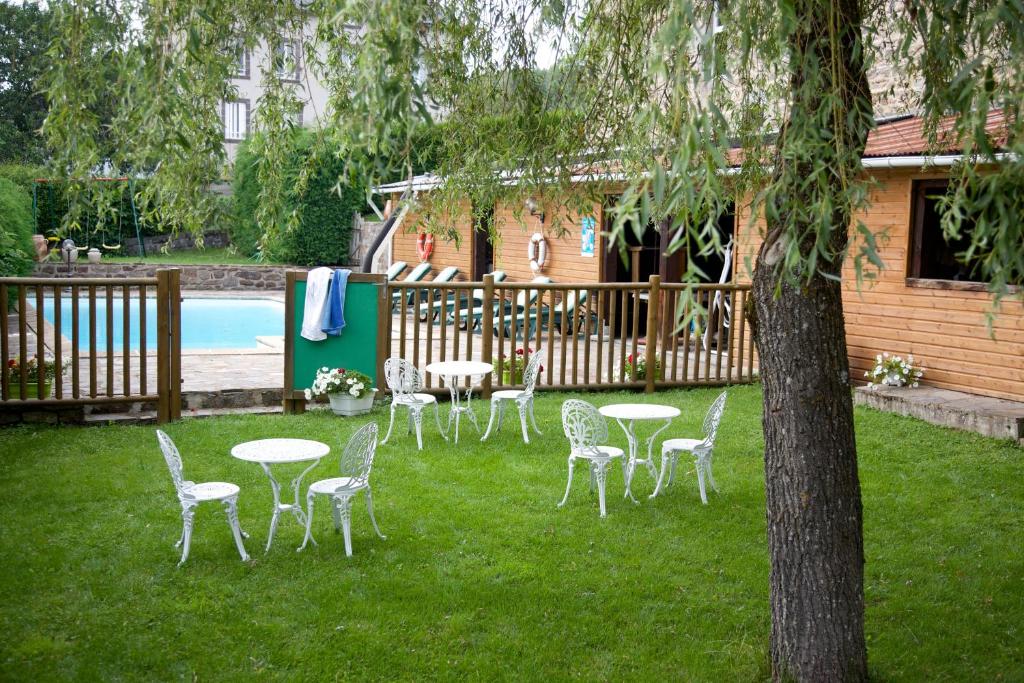 La Courtinelogis hôtel Le petit breuil的一组桌椅,位于带游泳池的院子内