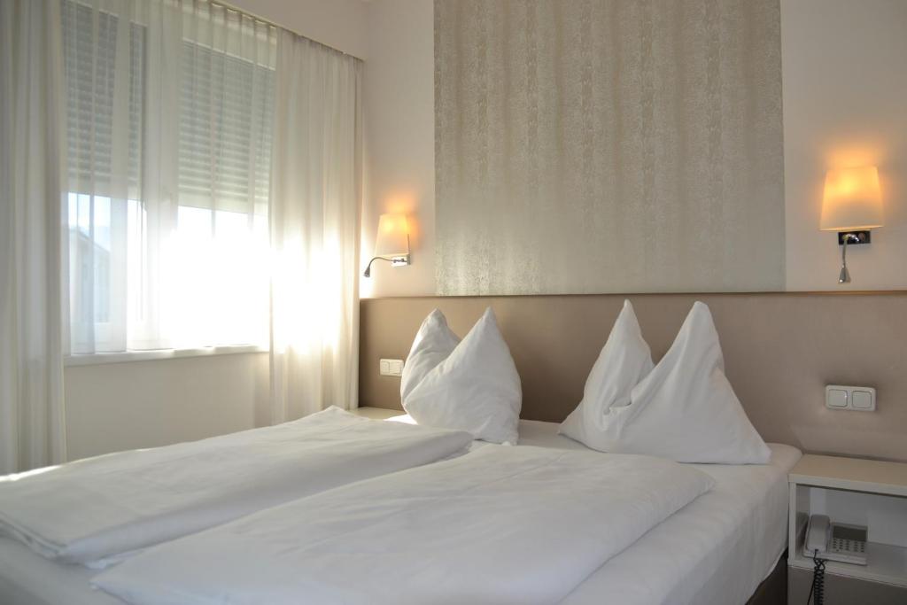 沃尔夫斯堡汉柯酒店的卧室内的白色床和白色枕头