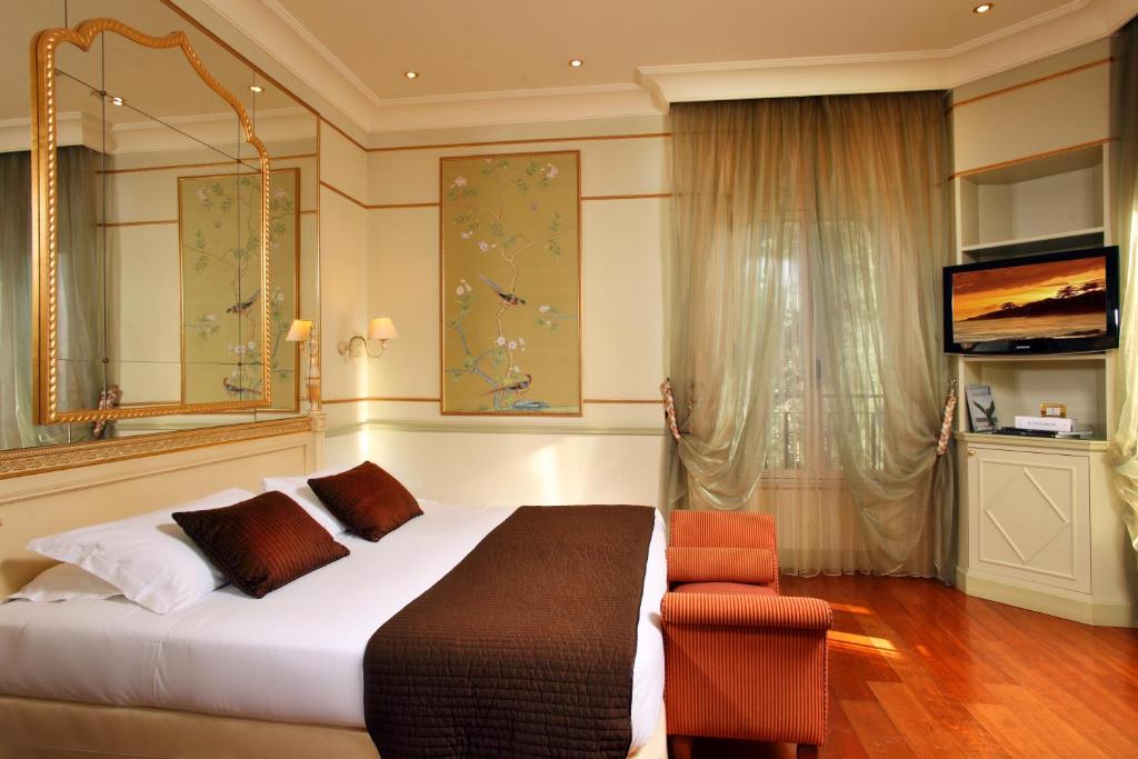 罗马德格里阿蓝希酒店的一间卧室配有一张床、一把椅子和电视