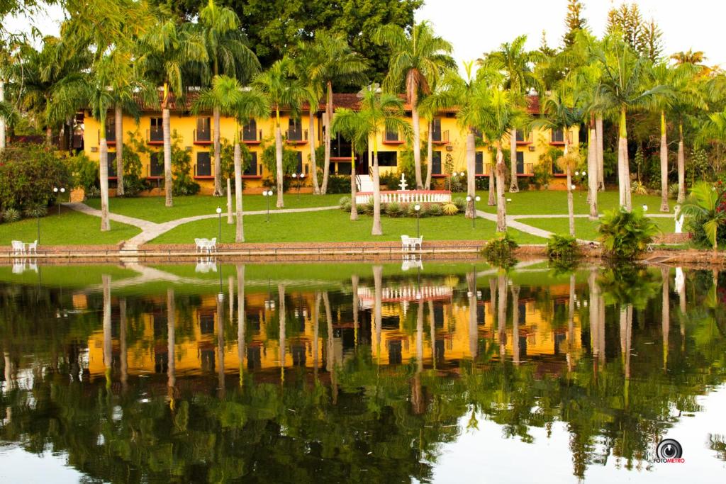 帕尔杜河畔圣若泽Hotel e Pousada Recanto do Rio Pardo的棕榈树和湖泊度假屋