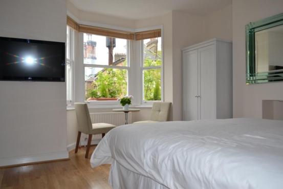 伦敦格罗弗69住宿加早餐旅馆的一间卧室配有一张床、一张桌子和一个窗户。