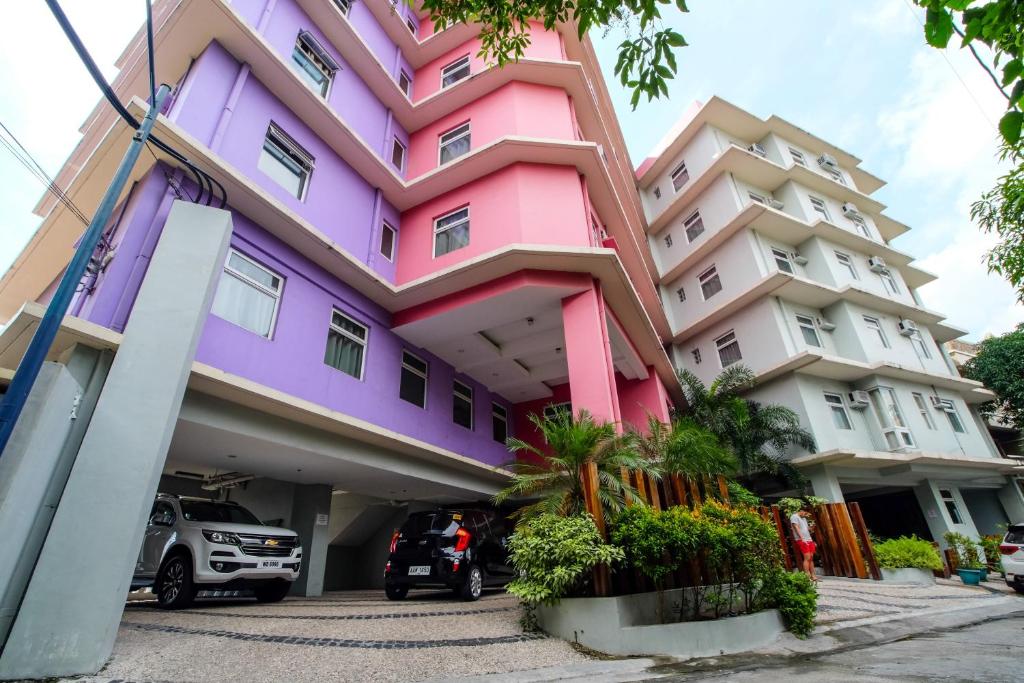 马尼拉MySpace Hotel @BGC的粉红色和紫色的建筑,设有停车场