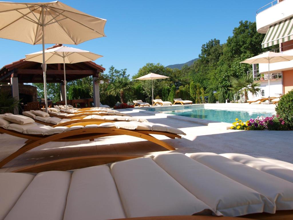 奥帕提亚Apartmani Učka的游泳池旁一排带遮阳伞的躺椅