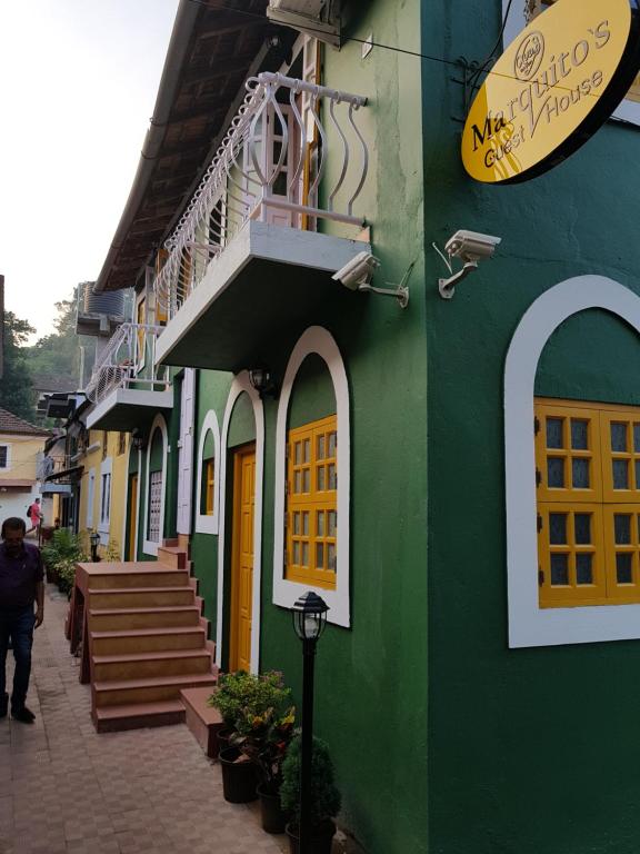 帕纳吉Marquito's Guest House的绿色建筑,街道上设有黄色门和楼梯