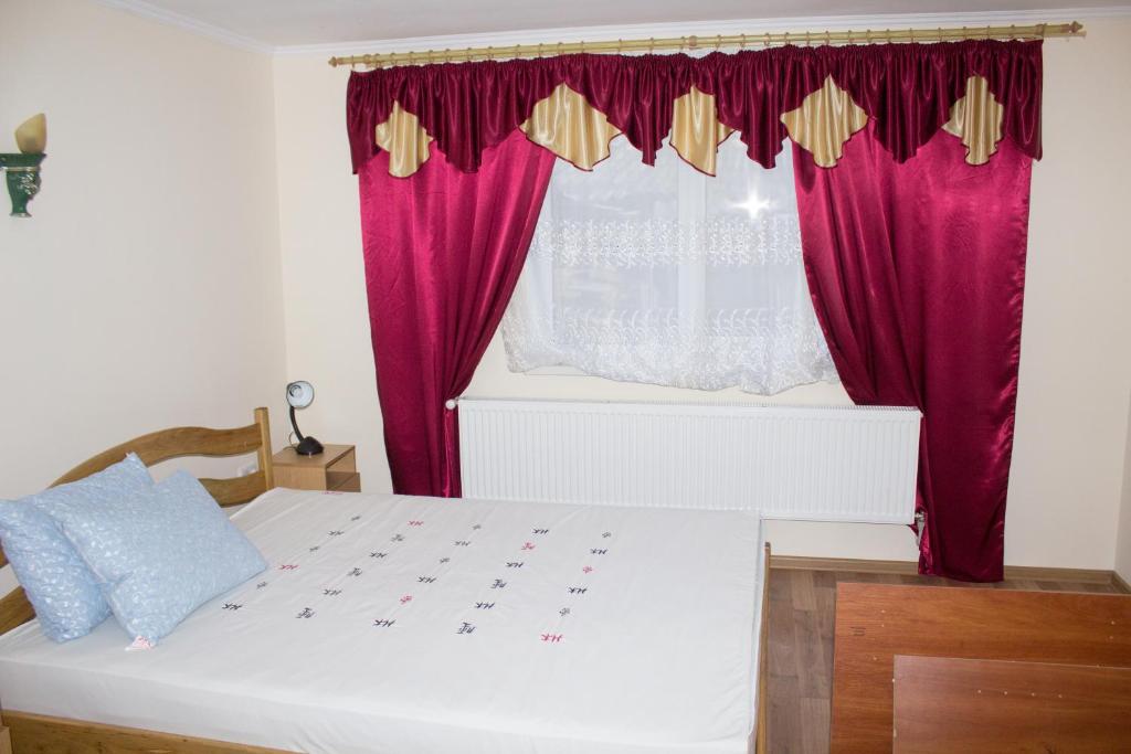 KhorostkivІмобільяре的卧室配有白色的床和红色窗帘