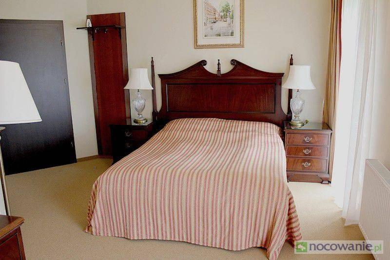 奥普尔Arkadia Gościniec的一间卧室配有一张带条纹毯子和两盏灯的床。