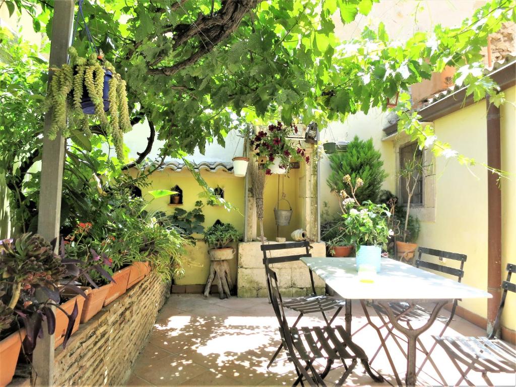 锡拉库扎La Casa Delle Fate的种有植物的庭院里摆放着桌椅