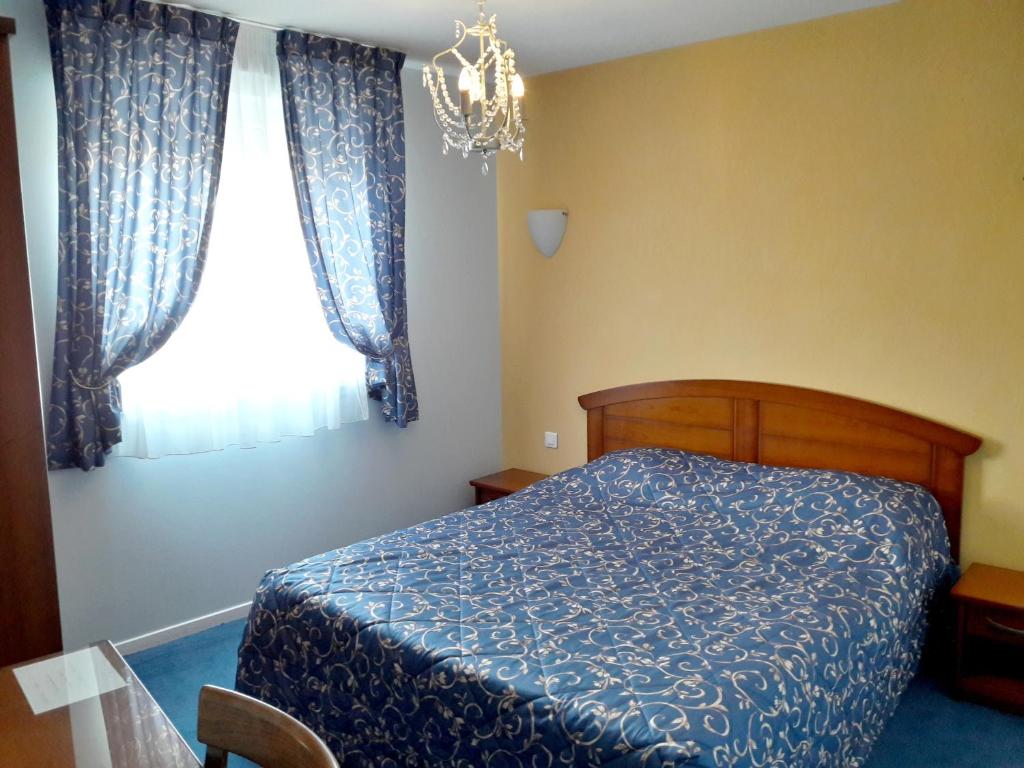 CorbenyLogis Hotel du Chemin des Dames的一间卧室设有蓝色的床和窗户。