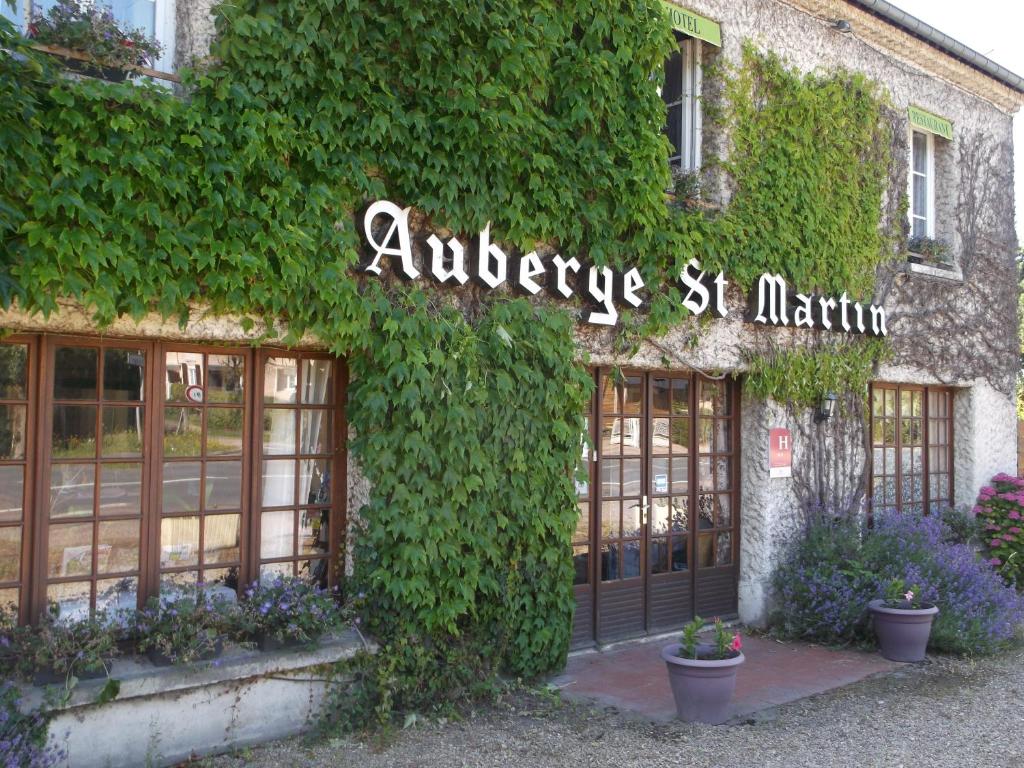 苏维Logis Hôtel Restaurant Auberge Saint Martin的常春藤覆盖的建筑,上面有读过 ⁇ 纹的标志