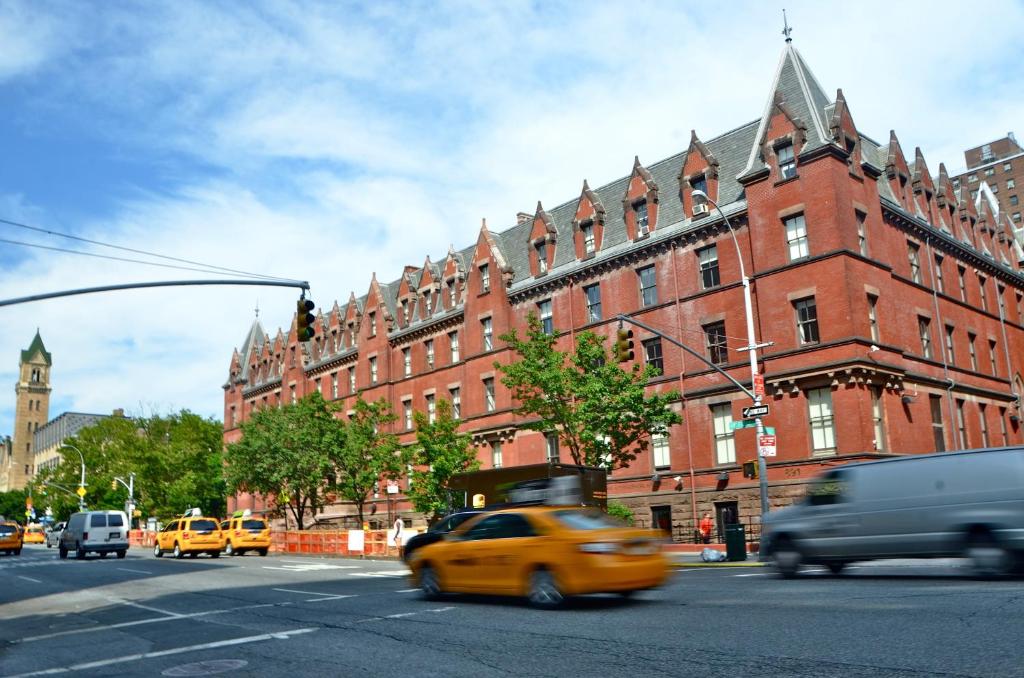 纽约HI New York City Hostel的一辆黄色的出租车驶过一座大型红砖建筑