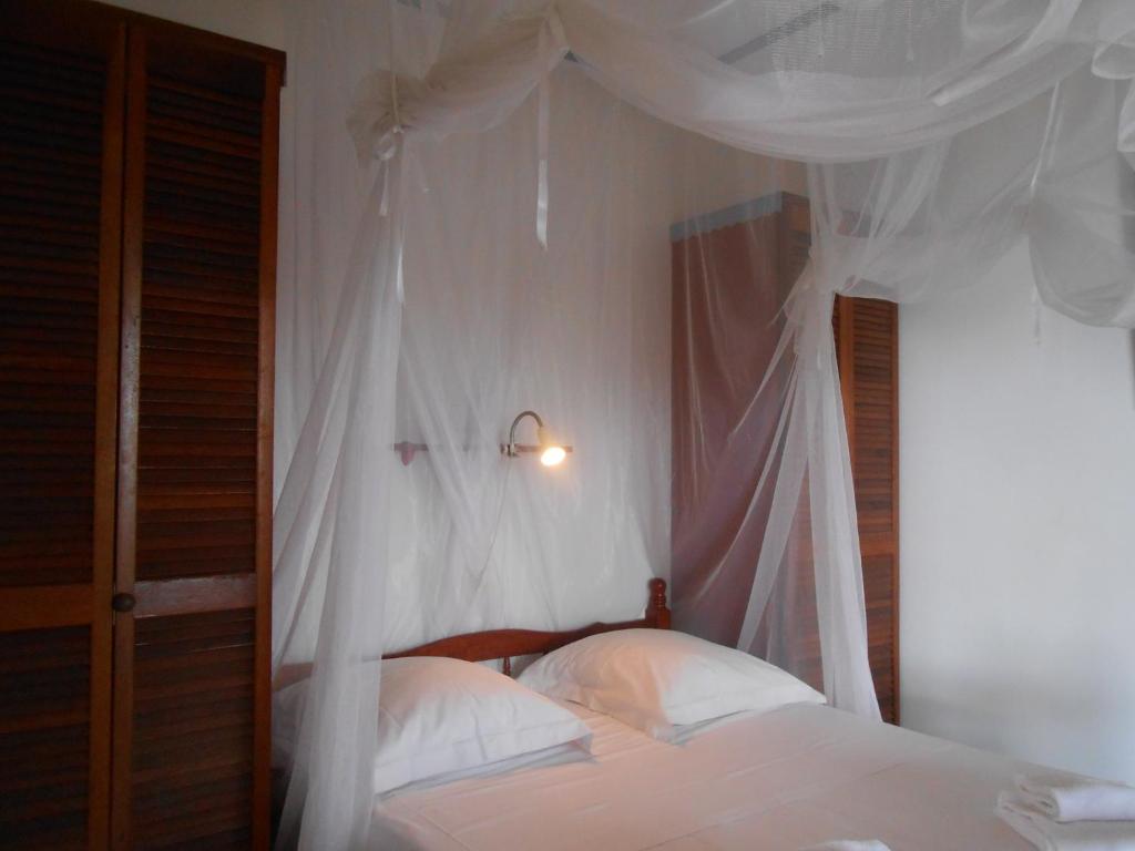 三河市BEL Z 'IGUANE的卧室配有带白色床单和枕头的天蓬床。