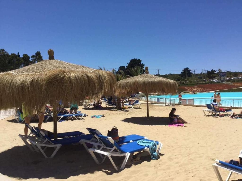 阿尔加罗沃Laguna Bahía, Algarrobo的海滩上摆放着椅子和草伞,人们