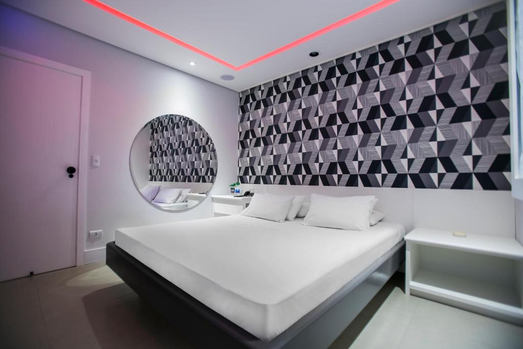 桑托斯骊威拉斯汽车旅馆（仅限成人）的卧室配有白色的床和镜子