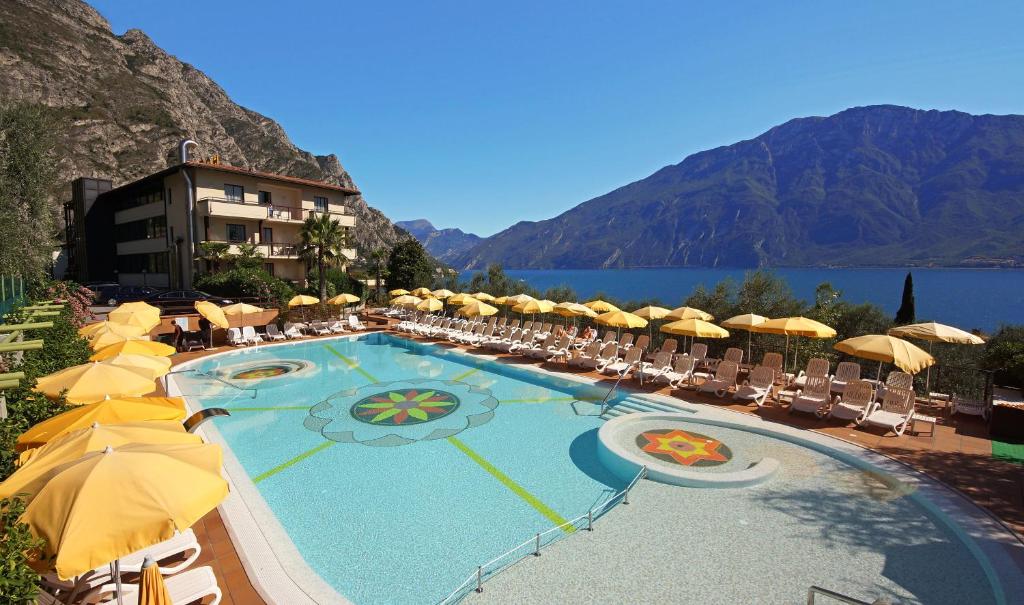 利莫内-苏尔加达Hotel Ilma Lake Garda Resort的一个带遮阳伞和椅子的游泳池以及酒店