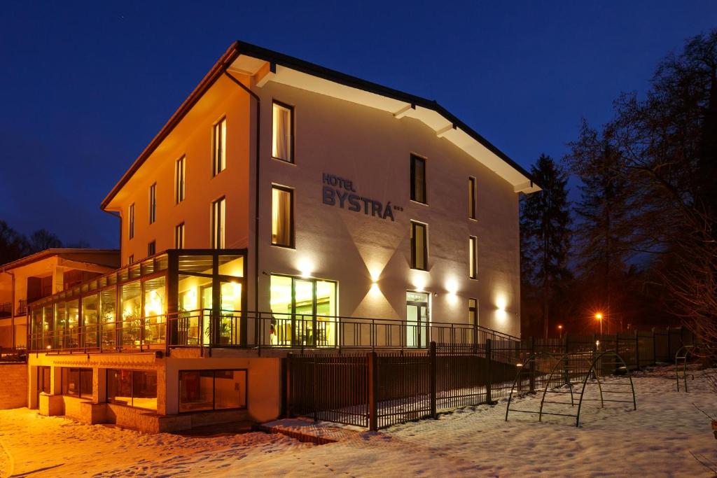 斯尼纳Hotel Bystrá的一座大建筑物,在晚上下雪