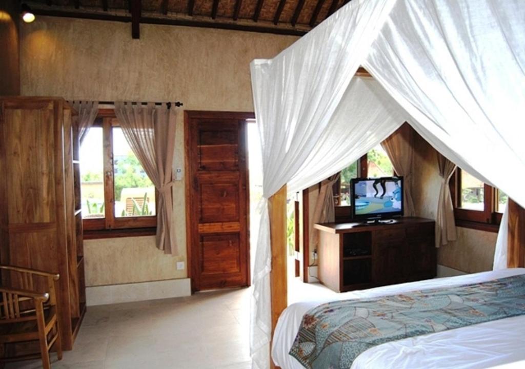 乌鲁瓦图三只猴子别墅酒店的一间卧室配有一张床和一台电视