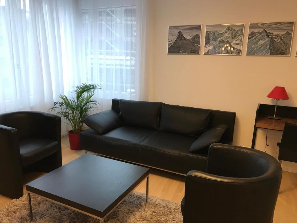 克洛滕Close to Zürich centre and Airport的客厅配有黑色沙发和两把椅子