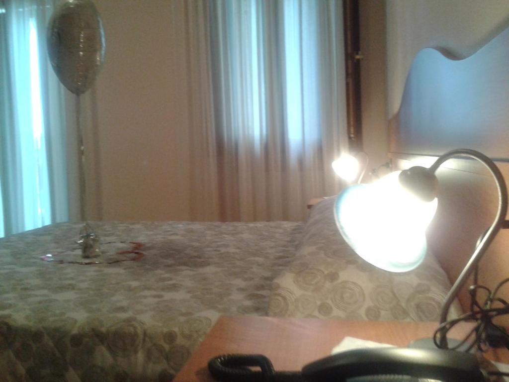 LusianaLocanda "Alla Rosa"的一间卧室配有一张带桌子和台灯的床