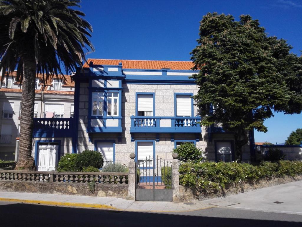 艾利亚德亚罗萨Casa Illa de Arousa, Galifornia!!的蓝白色的建筑,前面有一棵树