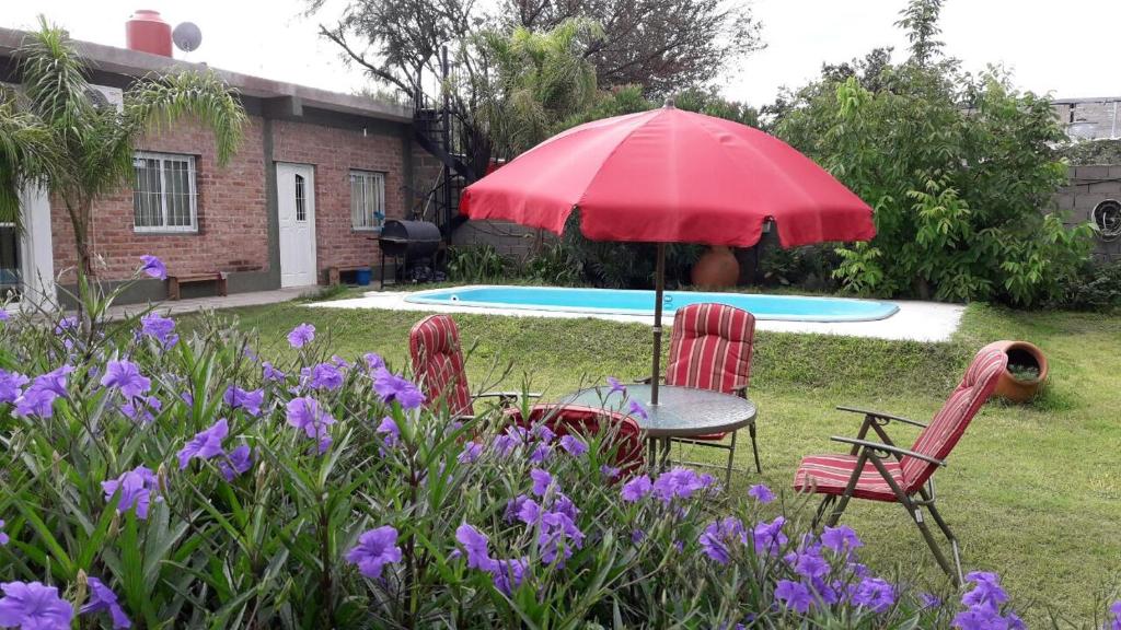 卡塔马卡La Chacarita apart的院子里设有两把椅子和一张桌子及一把遮阳伞