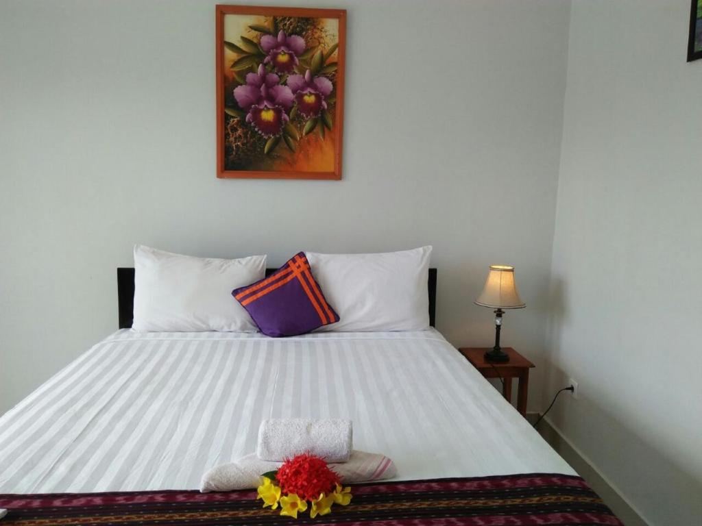 纳闽巴霍CF科莫多酒店的卧室配有一张白色的床,上面有一只动物填充物