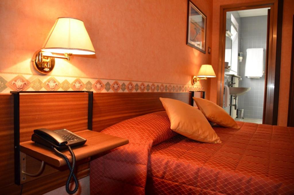 的里雅斯特米兰酒店的一间卧室配有一张床,桌子上配有电话