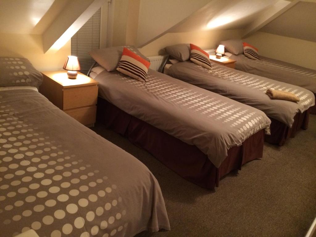 惠特利湾Melrose Guest House的一间设有三张床和两张台灯的房间