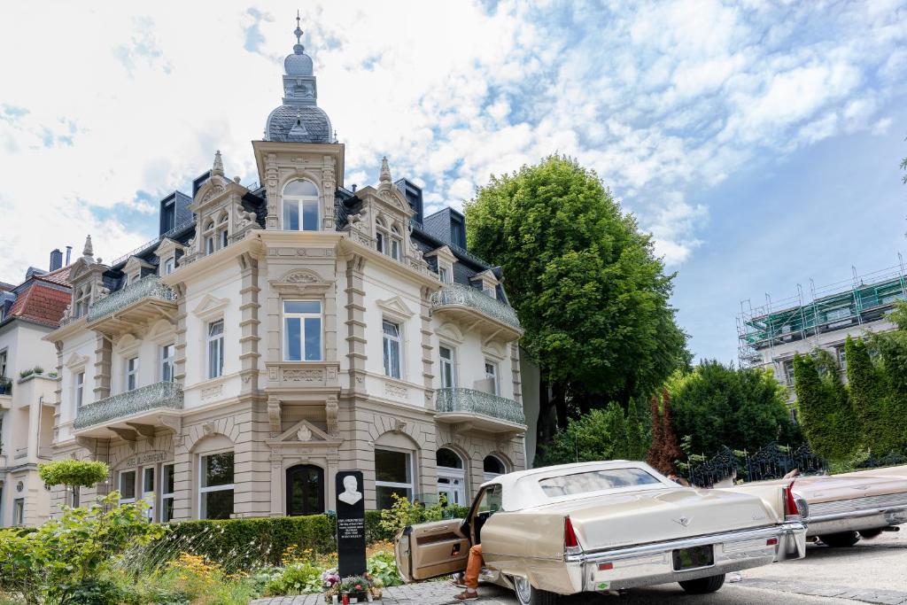 巴特瑙海姆格鲁内瓦尔德别墅酒店的停在一座带钟楼建筑前面的白色汽车
