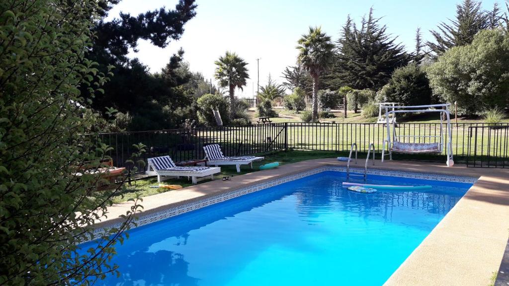 阿尔加罗沃Algarrobo Casa Campo ALYWEN的蓝色游泳池,带两把椅子和围栏
