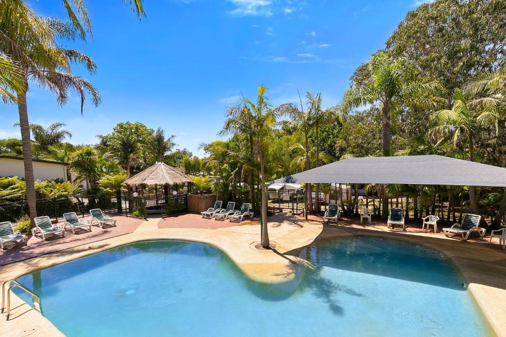 卡尔斯Kaloha Holiday Resort Phillip Island的一个带椅子和遮阳伞的大型游泳池