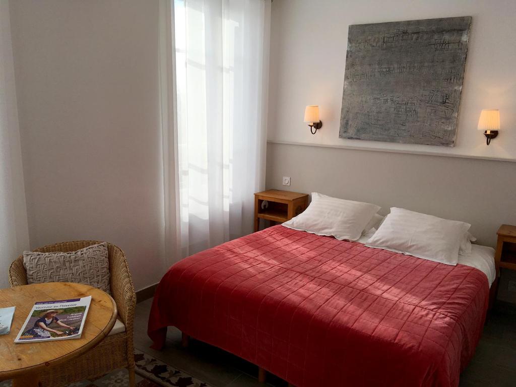 贝端加兰斯酒店的一间卧室配有一张带红色毯子和桌子的床。