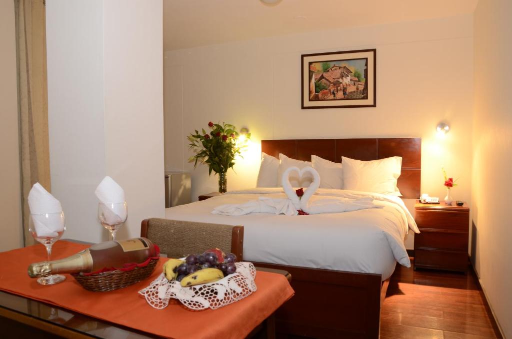 库斯科金印加酒店的一间卧室配有一张床铺,桌上有水果篮