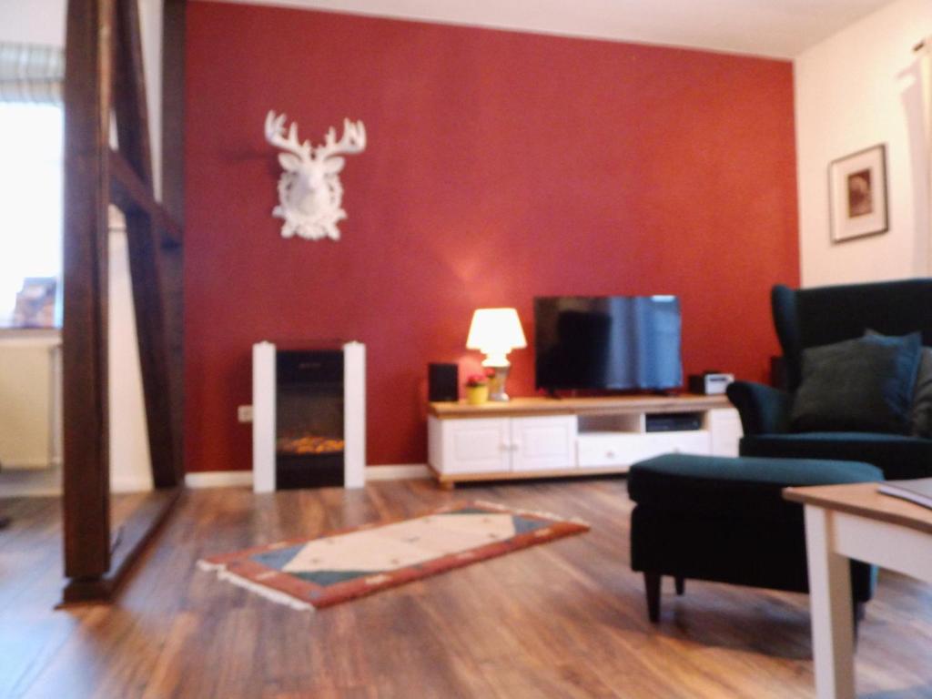 哈嫩克利博克斯维斯Harzglück的客厅设有红色墙壁,墙上挂着鹿头
