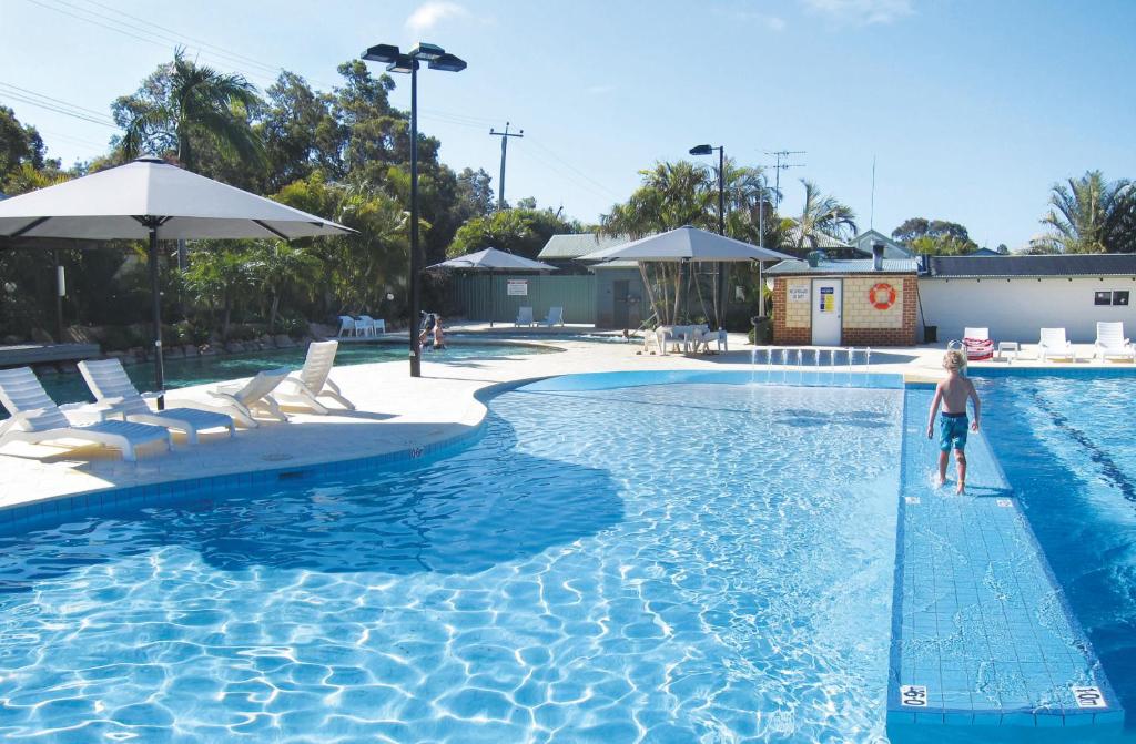 珀斯卡日恩玉普水域度假酒店的站在游泳池的水面上的男孩
