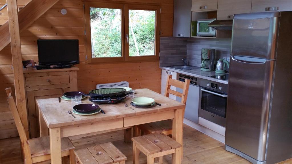 奥雷勒La cabane du pommier的厨房配有木桌、炉灶和冰箱。